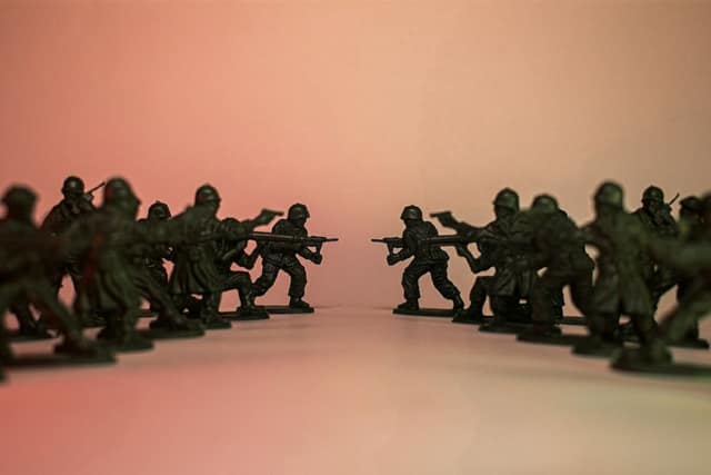 Two lines of green toy soldiers facing each other on a pink background