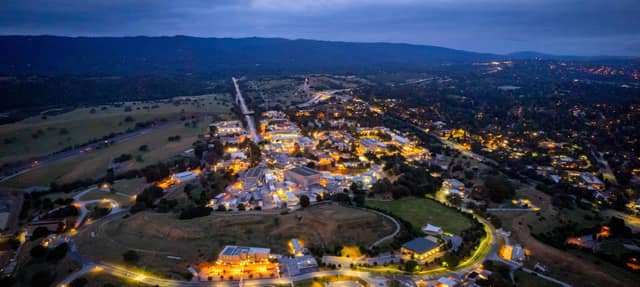 Aerial view at dusk of the SLAC National Accelerator Laboratory campus and the LCLS linear accelerator